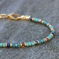 A zoomed-in image of the clasp and end beads of a turquoise anklet with mixed color accents.
