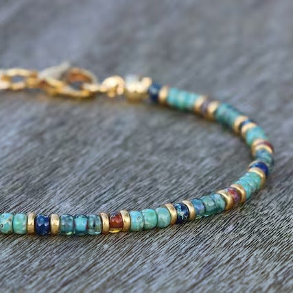 A zoomed-in image of the clasp and end beads of a turquoise anklet with mixed color accents.