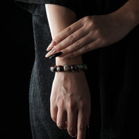 A natural-toned Island Aquamarine bracelet with round beads, worn on the wrist against a black outfit.