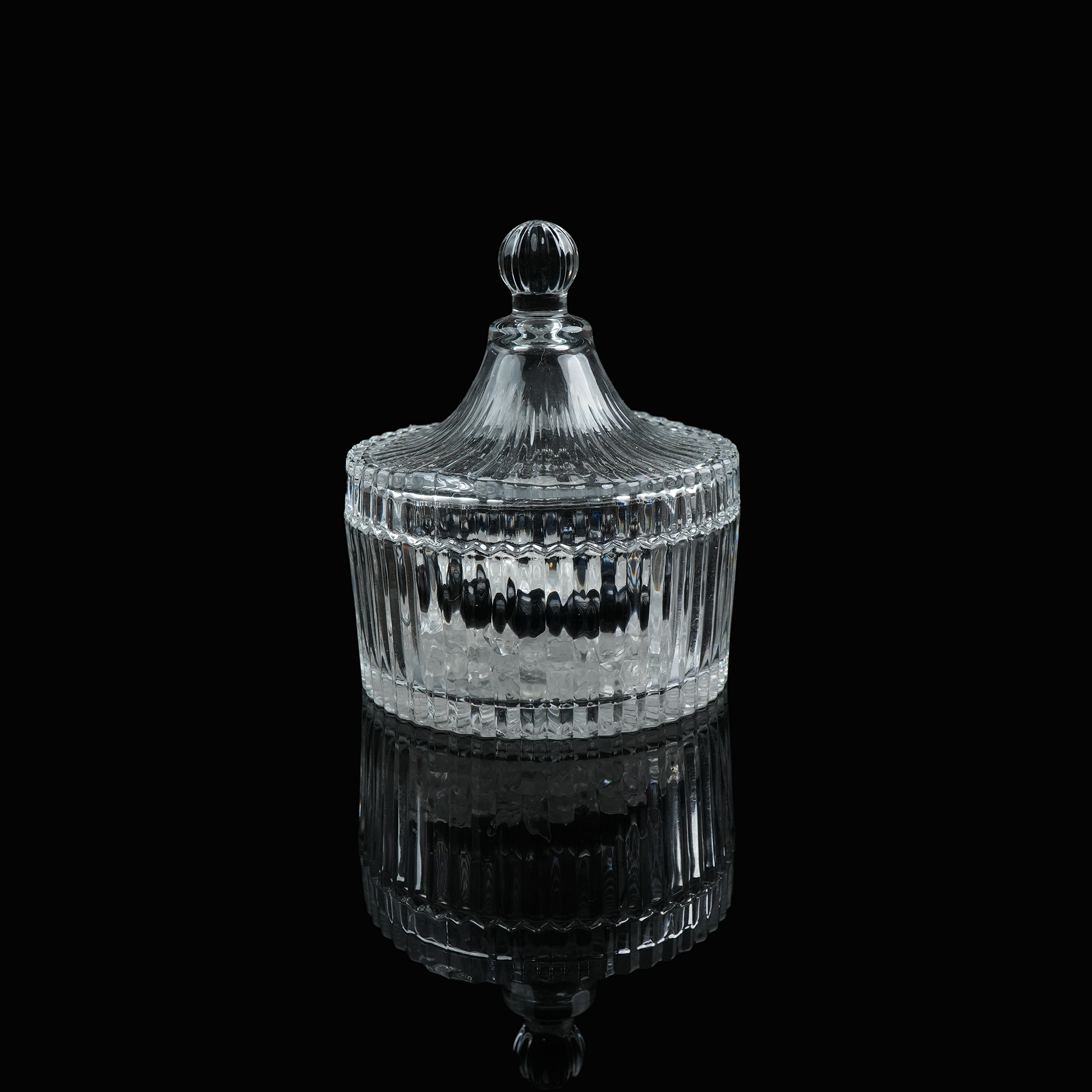 A small glass crystal charging bowl with a lid, photographed from a distance to show its elegant form.