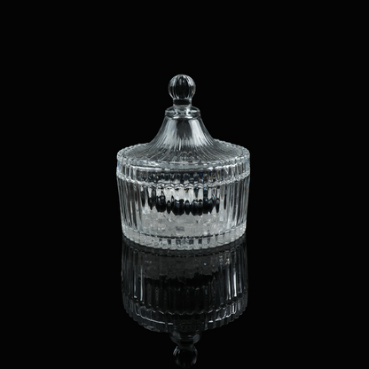 A small glass crystal charging bowl with a lid, photographed from a distance to show its elegant form.