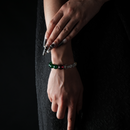 Hand wearing a bracelet composed of clear quartz, green agate, garnet, and a gold-tone spacer bead.