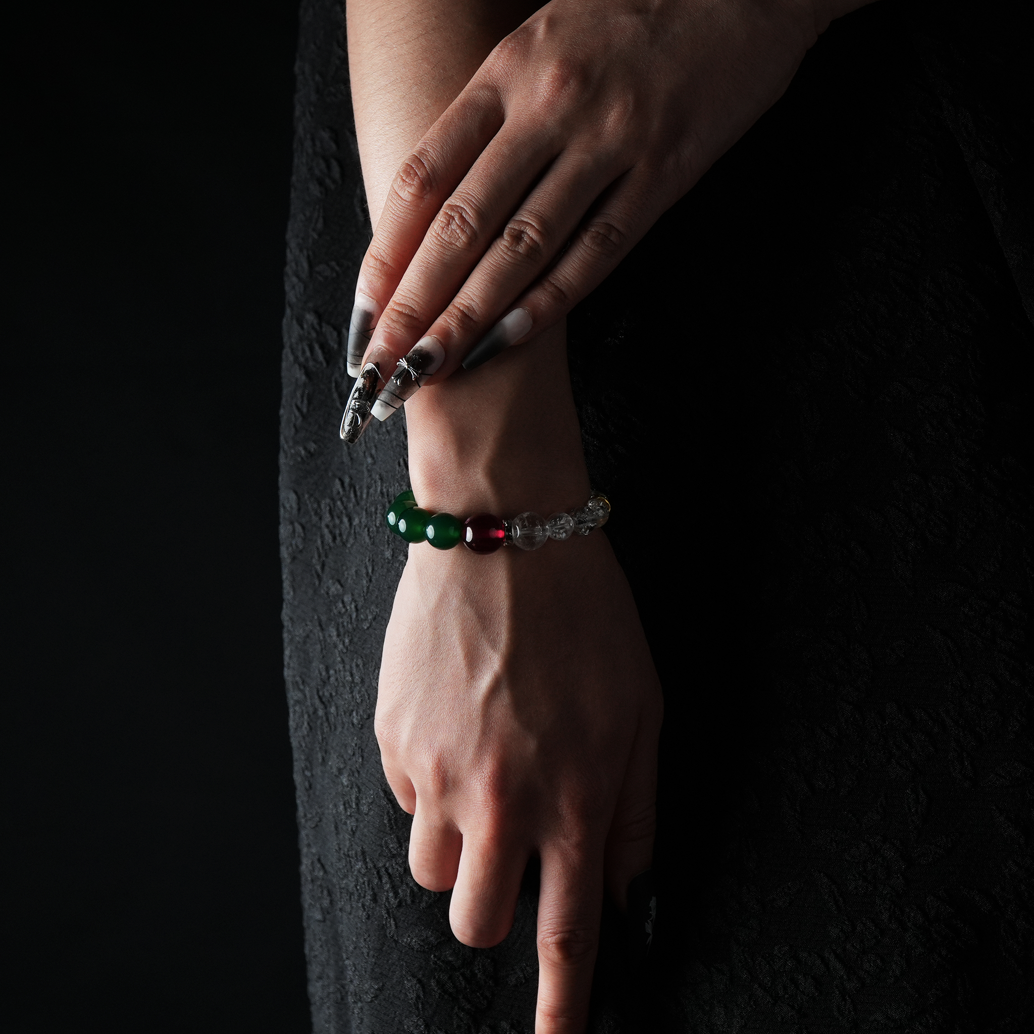 Hand wearing a bracelet composed of clear quartz, green agate, garnet, and a gold-tone spacer bead.