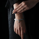 A model wearing a gemstone bracelet composed of grey moonstone and Himalayan quartz, with silver charms resting softly on the wrist.