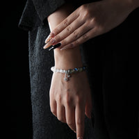 A model wearing a gemstone bracelet composed of grey moonstone and Himalayan quartz, with silver charms resting softly on the wrist.