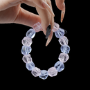 A hand holding the natural raw purple crystal bracelet, showcasing its rough texture and vibrant purple colors against a dark backdrop.