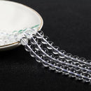 Translucent crystal beads cascading from a plate, emphasizing their round cut and high polish.