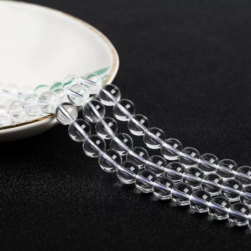 Translucent crystal beads cascading from a plate, emphasizing their round cut and high polish.