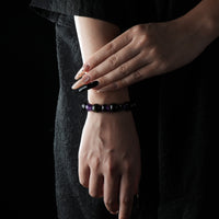 A simple black and purple bracelet made of obsidian and amethyst, worn on the wrist.