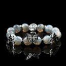 Handmade opalite energy bead bracelet with silver butterfly charms, radiating a mystical glow on a glossy black background.