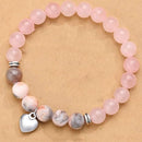 A bracelet with pink beads and natural stones arranged on a neutral brown background, showcasing its gentle and harmonious design.