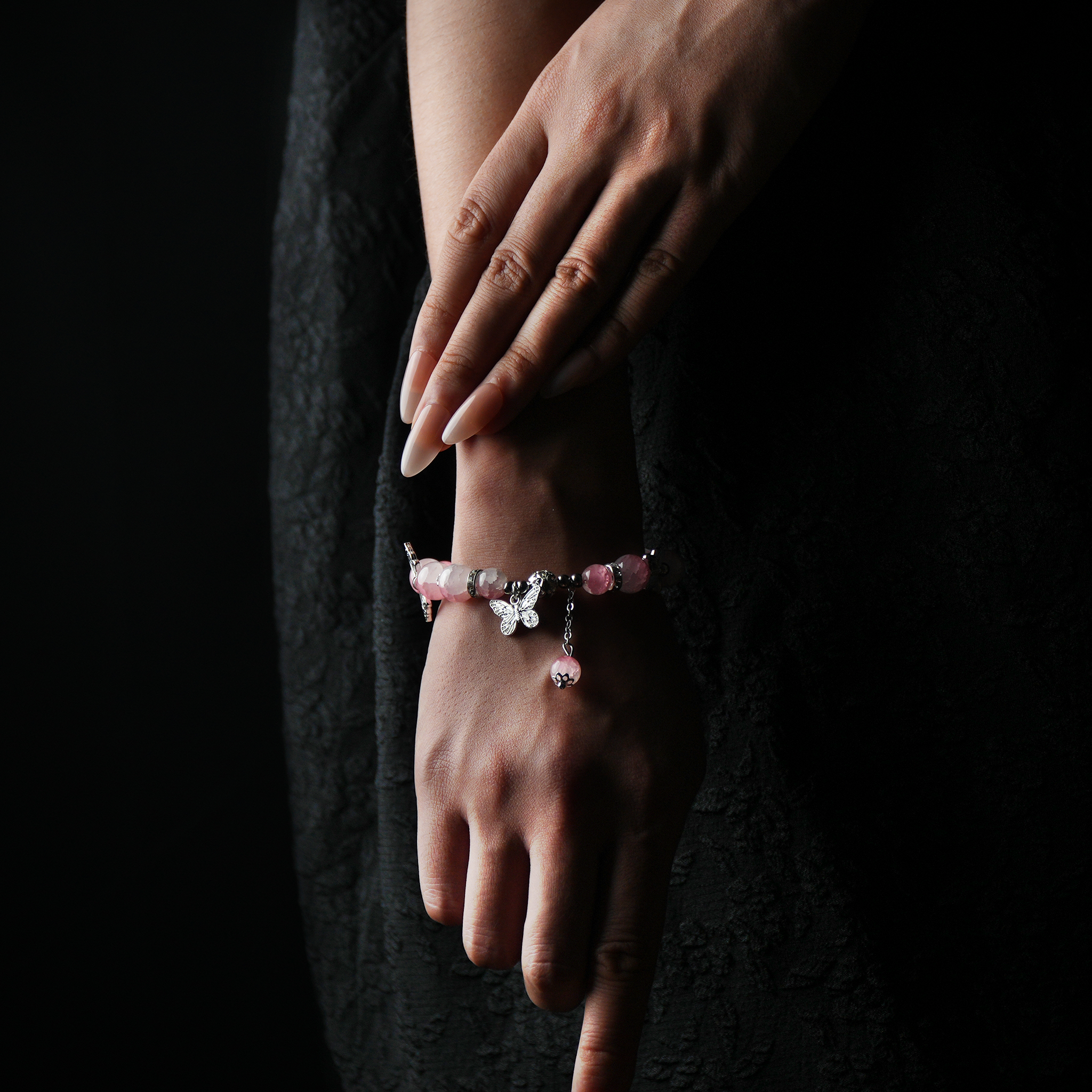 Feminine rose quartz energy bead bracelet with symbolic butterfly charms worn on hand, promoting emotional healing, love, and gentle energy alignment.