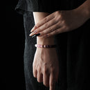 A bracelet featuring rose quartz, strawberry quartz, and garnet beads, worn on the wrist against a black lace outfit.