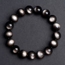 A silver sheen obsidian bracelet placed on a gray background, with noticeable contrast between black beads and silver luster.