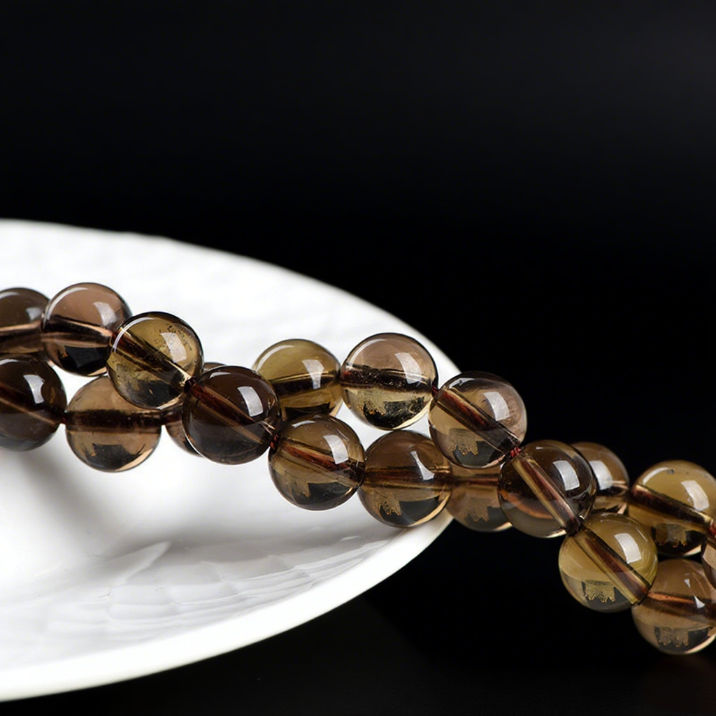 Natural smoky quartz round beads rest against a white ceramic plate. The beads have a rich amber-to-brown gradient and polished surfaces that reflect light gently against the contrasting black and white backdrop.