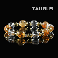 Flat lay of Taurus zodiac bracelet with golden citrine, clear quartz, and golden rutile crystal beads on black reflective background.