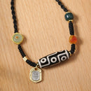 The Tibetan 9-eye agate Dzi bead necklace on a wooden background, showcasing its intricate beadwork and gold charm detail.