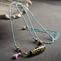 The Tibetan Agate Dzi Bead Necklace, showcasing a detailed view of the dzi bead design, red agate, and black agate beads with intricate golden accents.