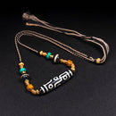 A handcrafted Tibetan Nine-Eye Agate Dzi bead necklace featuring turquoise, black agate, and golden spacers, displayed against a black backdrop for emphasis on the intricate design.