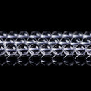 Transparent crystal beads arranged neatly on a reflective surface, showcasing clarity and shine.