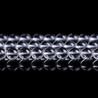 Transparent crystal beads arranged neatly on a reflective surface, showcasing clarity and shine.