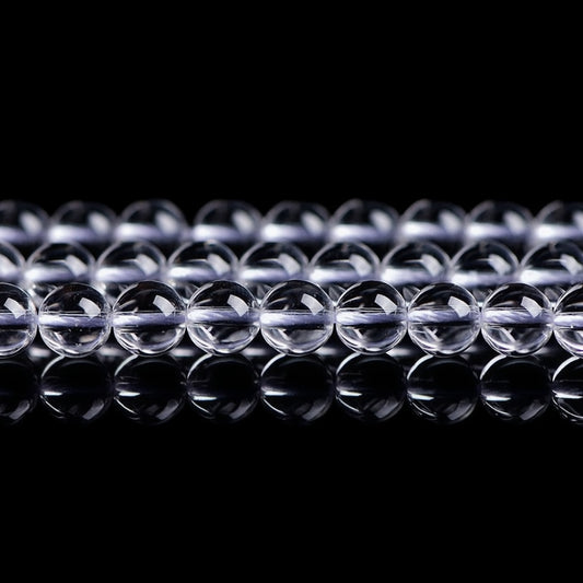 Transparent crystal beads arranged neatly on a reflective surface, showcasing clarity and shine.