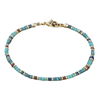 A turquoise bead anklet with gold clasp shown on a white background, highlighting its delicate structure.