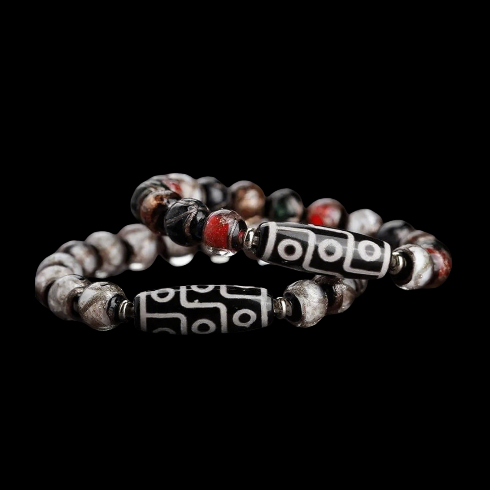 A pair of vintage-style Tibetan bracelets featuring classic black and white 9-eye Dzi beads. The surrounding round beads come in a weathered palette of red, gray, and black, creating a rustic, well-worn aesthetic. Shot on a black background to emphasize the traditional craftsmanship.