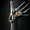 Capricorn zodiac bracelet worn on black mannequin hand, showcasing earthy healing stones like lava rock, tiger eye, obsidian, and quartz.