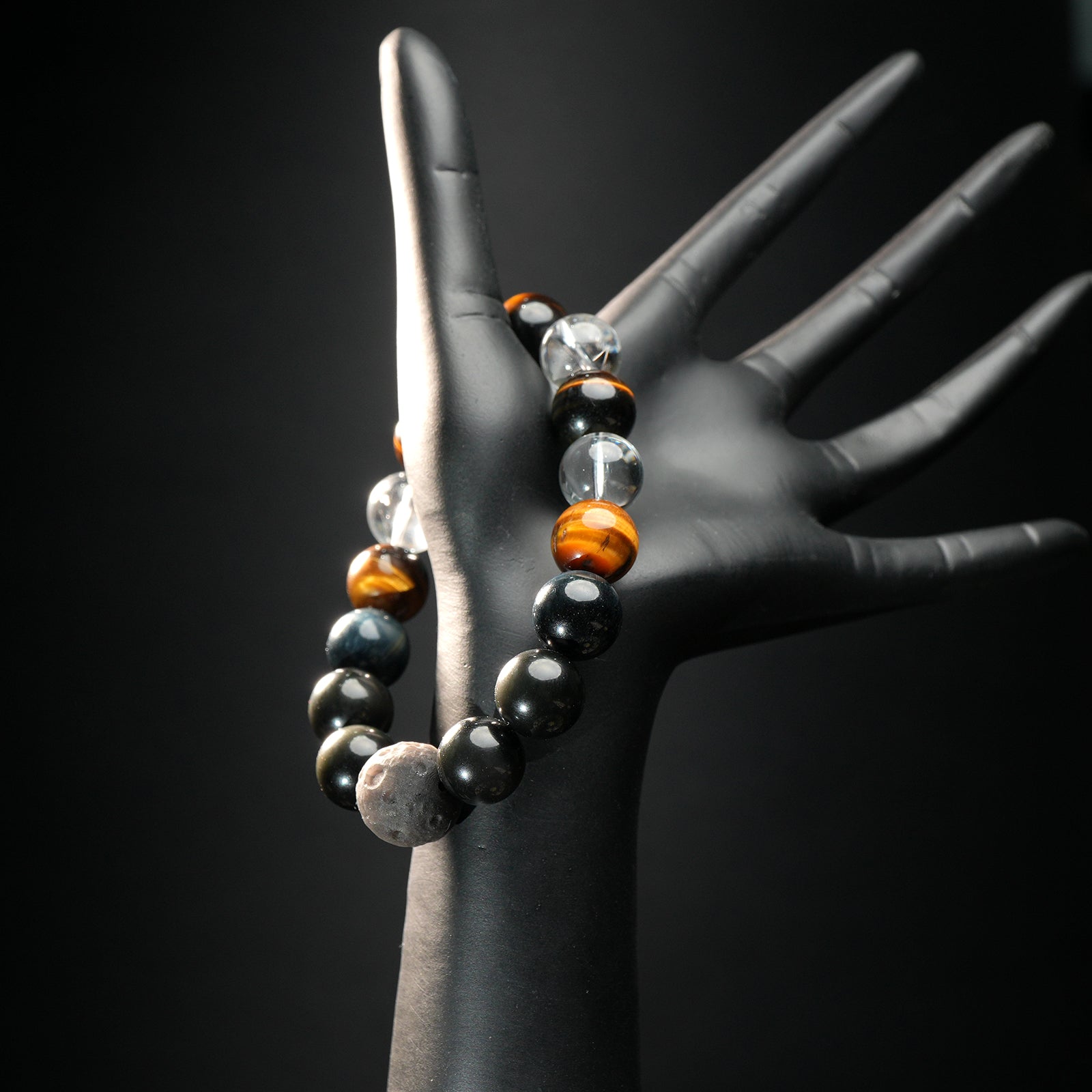 Capricorn zodiac bracelet worn on black mannequin hand, showcasing earthy healing stones like lava rock, tiger eye, obsidian, and quartz.