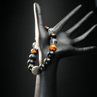 Capricorn zodiac bracelet worn on black mannequin hand, showcasing earthy healing stones like lava rock, tiger eye, obsidian, and quartz.