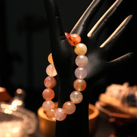 Bracelet styled on a black mannequin hand, lit with warm glow to enhance the vibrant red and amber hues, conveying balance and vitality.
