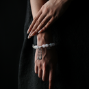 A graceful wrist adorned with a glowing energy bead bracelet featuring a silver Xiangyun (auspicious cloud) charm and dangling tassels, embodying peace, culture, and spiritual alignment.