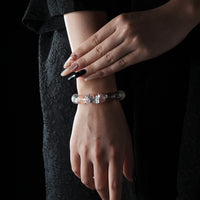 A stylish bracelet made of strawberry quartz and clear quartz beads with a silver butterfly charm, elegantly worn on the wrist.