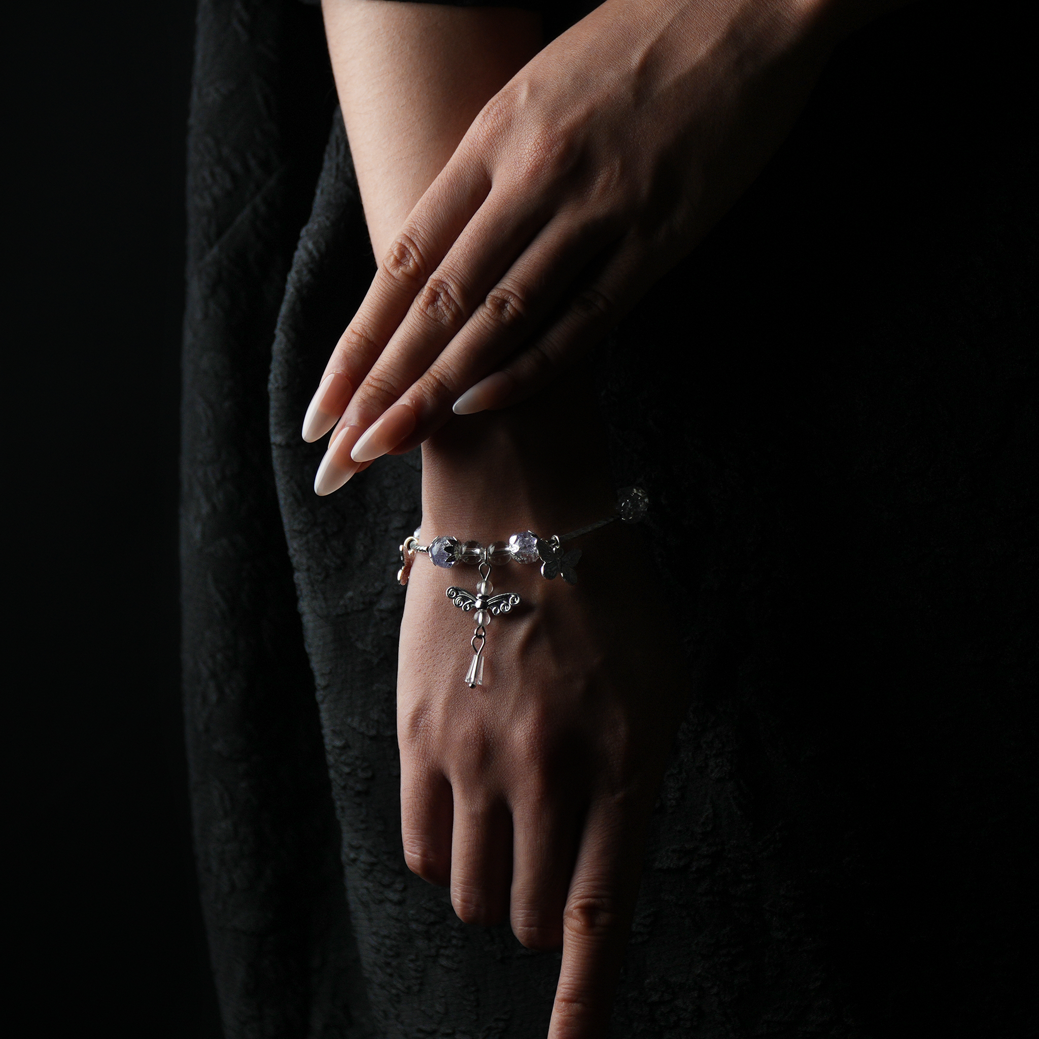 Wrist adorned with a silver-toned crystal energy bracelet featuring butterfly and dragonfly charms, reflecting intuition, freedom, and inner transformation.