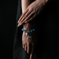 A gradient blue energy bead bracelet gracefully wraps the wrist, evoking the depth and calm of the ocean, while the butterfly charm sparkles like starlight in motion.