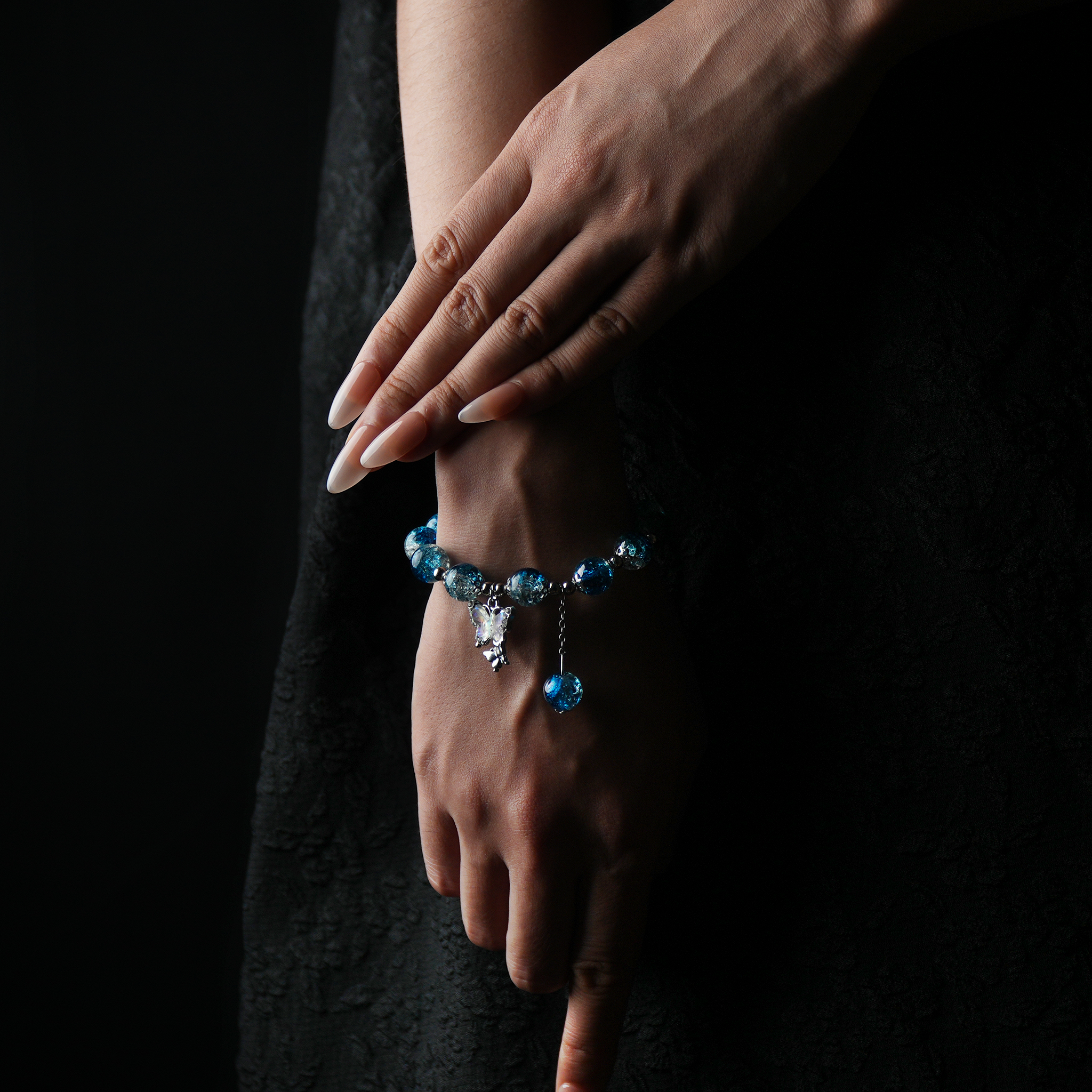 A gradient blue energy bead bracelet gracefully wraps the wrist, evoking the depth and calm of the ocean, while the butterfly charm sparkles like starlight in motion.