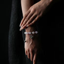 A wrist adorned with a pink and purple energy bead bracelet, softly shimmering with a silver butterfly charm—sweet, romantic, and full of graceful energy.
