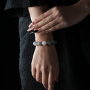 A person wearing a rose quartz and gray moonstone bracelet, styled with a black outfit to highlight the calming colors and elegant stone arrangement.