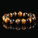 A close-up of a yellow tiger eye bracelet on a black reflective surface, showcasing the rich golden-brown bands and polished shine.