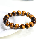 A round yellow tiger eye bracelet resting on curved white porcelain, showing natural luster and color variation.