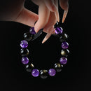 Amethyst and golden obsidian beaded bracelet held by hand on black background for protection and spiritual clarity.