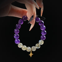 Amethyst and labradorite beaded bracelet with gold star charm, held by hand on black background for spiritual protection and intuition.
