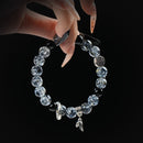 Black rutilated quartz beaded bracelet with silver charms and symbols, held by hand on black background for strength and protection.