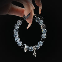 Black rutilated quartz beaded bracelet with silver charms and symbols, held by hand on black background for strength and protection.
