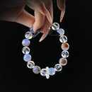 Elegant bracelet featuring alternating blue agate and clear quartz beads with natural patterns, held by hand against a black background.