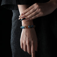 Stylish bracelet made of faceted blue and amber-hued beads, worn on a woman's wrist dressed in black.