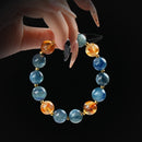 Blue kyanite and citrine beaded bracelet with gold spacers, held by hand on black background for clarity and energy.