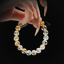 Citrine sunshine beaded bracelet with golden tones, held by hand on black background for abundance and positive energy.