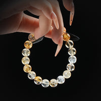 Citrine sunshine beaded bracelet with golden tones, held by hand on black background for abundance and positive energy.